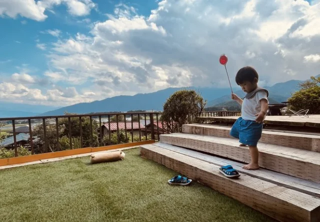 山を望むテラスで風船を持つ子ども